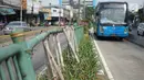 Sejumlah bambu menopang pagar pembatas jalur transjakarta di Jalan Otista Raya, Jakarta, Jumat (5/7/2019). Meskipun telah lama rusak, pagar besi berjeruji yang berfungsi sebagai pembatas agar orang tidak menyeberang secara sembarangan itu belum juga diperbaiki. (Liputan6.com/Immanuel Antonius)