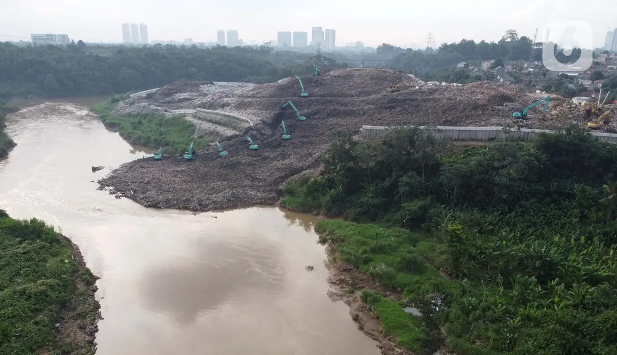 Foto udara memperlihatkan alat berat memindahkan tumpukan sampah dari Tempat Pembuangan Akhir (TPA) Cipeucang yang masuk ke area Sungai Cisadane, Serpong, Tangerang Selatan, Rabu (3/6/2020). Sebelumnya, pada Jumat (22/5/) lalu turap yang menopang TPA tersebut jebol. (Liputan6.com/Helmi Fithriansyah)