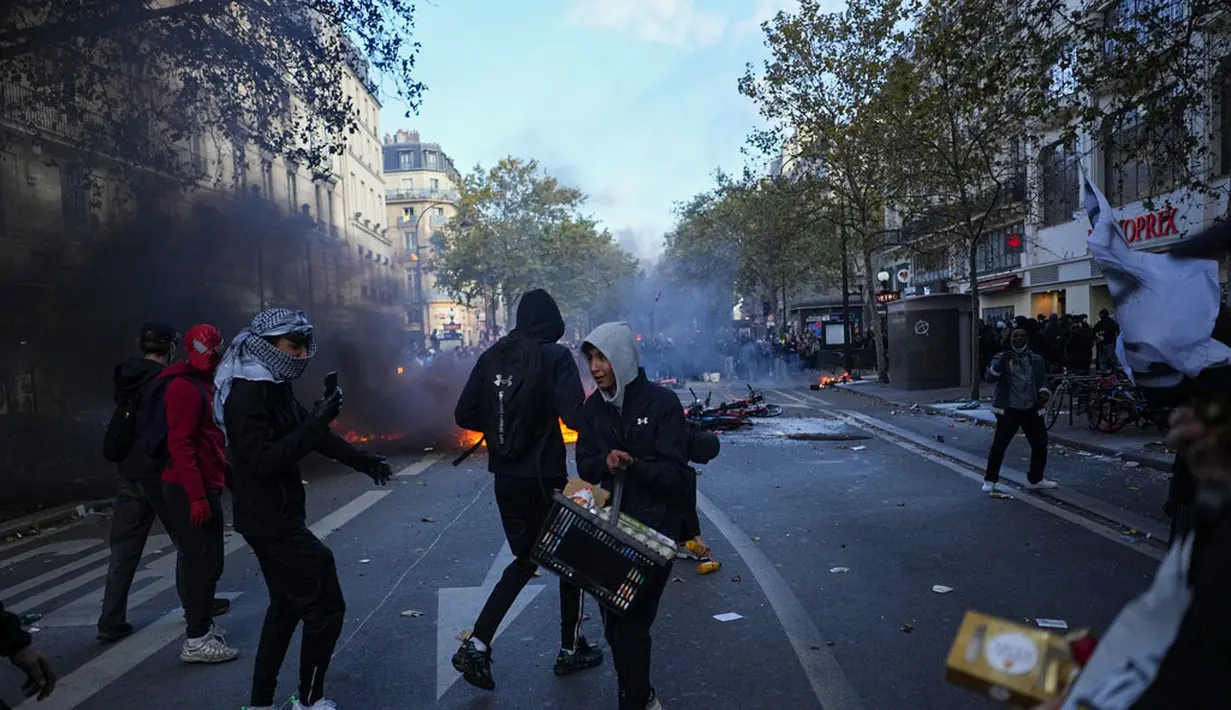 Sejumlah demonstran berdiri di depan sepeda yang terbakar saat aksi menentang kenaikan biaya hidup sekaligus menyuarakan tuntutan mahasiswa di Paris, Prancis, Sabtu (17/10/2026). (AP Photo/Thibault Camus)