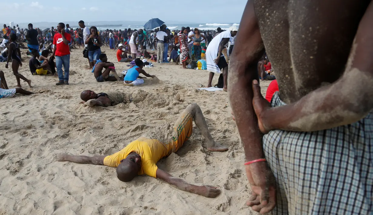 Sejumlah pengunjung mengubur diri dengan pasir saat liburan awal Tahun Baru 2017 di sebuah pantai di Durban, Afrika Selatan (1/1). (REUTERS/Rogan Ward)