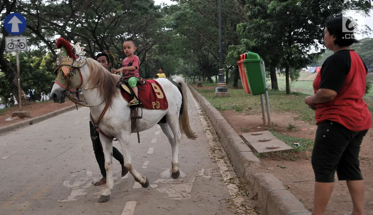 Seorang anak menunggangi kuda di kawasan Kanal Banjir Timur, Jakarta, Selasa (5/6). Berkuda mengelilingi kawasan Kanal Banjir Timur menjadi salah satu pilihan warga untuk ngabuburit sembari mengajak anak-anak bermain. (Merdeka.com/Iqbal S. Nugroho)
