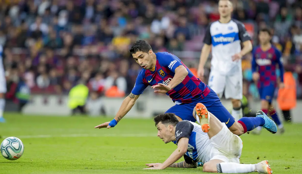 Striker Barcelona, Luis Suarez, terjatuh saat berusaha melewati pemain Deportivo Alaves pada laga La Liga 2019 di Stadion Camp Nou, Sabtu (21/12). Barcelona menang 4-1 atas Deportivo Alaves. (AP/Joan Monfort)