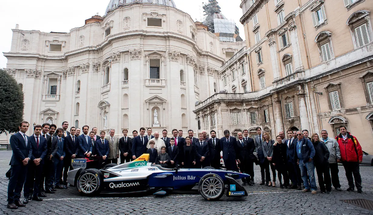 Paus Fransiskus berfoto bersama perwakilan manajer dan pengemudi Kejuaraan Formula FIA ABB di belakang mobil balap listrik Formula E di Vatikan (11/4). (AFP Photo/Media Vatikan)