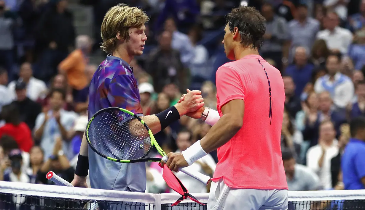 Petenis asal Spanyol, Rafael Nadal dan petenis Rusia, Andrey Rublev berjabat tangan seusai laga perempatfinal turnamen AS Terbuka 2017 di New York, Rabu (6/9). Nadal melangkah ke semifinal usai mengalahkan petenis 19 tahun itu. (Clive Brunskill/AFP)