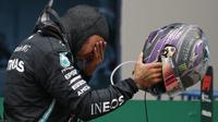 Pembalap Mercedes Lewis Hamilton dari Inggris menangis setelah memenangkan Grand Prix Formula Satu Turki di arena pacuan kuda Istanbul Park di Istanbul, Minggu (15/11/2020). (AP Photo/Kenan Asyali, Pool)