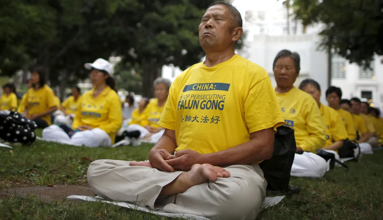 Salah satu aktivis melakukan meditasi Falun Gong sebelum demonstrasi menentang pemerintah China, di luar Balaikota Los Angeles, California, Kamis (15/10). Presiden China Xi Jinping akan melakukan kunjungan kenegaraan di Washington.(REUTERS/Lucy Nicholson)