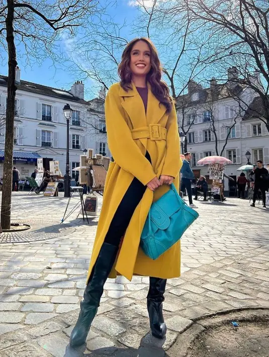 Tampilan modis Cinta Laura yang memadukan long coat warna mustard, burgundy top, celana panjang hitam, dan sepatu boots ini juga menarik untuk disontek. (Instagram/claurakiehl).
