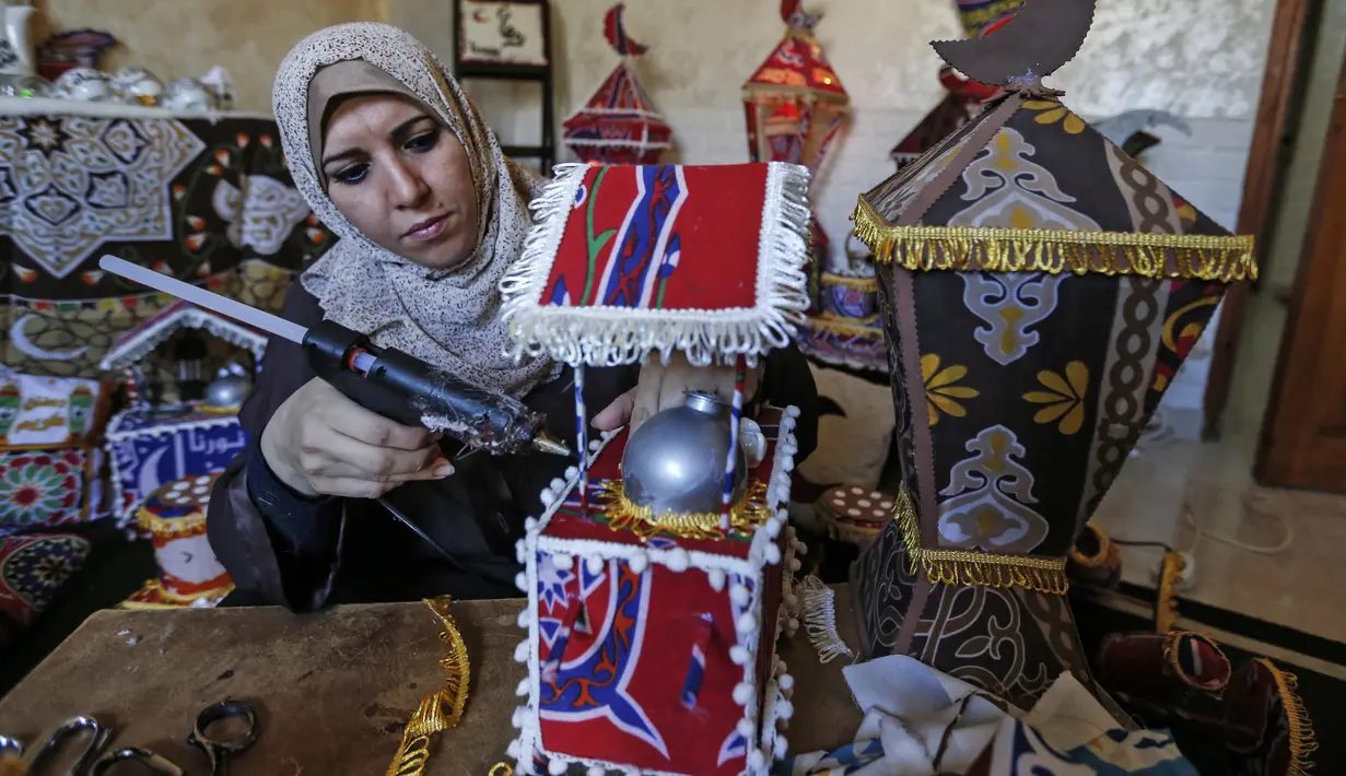 Hanan al-Madhoun (37) menyelesaikan pembuatan lentera tradisional yang disebut "fanous" di rumahnya di Kota Gaza, menjelang bulan suci Ramadan dan di tengah pandemi corona, pada 1 April 2021. Warga biasanya memasang lentara sebagai dekorasi untuk merayakan dimulainya Ramadan. (MAHMUD HAMS / AFP)