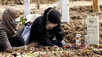 Seorang wanita menangis saat mengunjungi makam kerabat yang meninggal karena COVID-19 di TPU Rorotan, Jakarta, Rabu (7/7/2021). Di seluruh negeri, virus corona COVID-19 kembali menyebar dengan cepat dengan meledak di luar kapasitas dan pasokan oksigen habis. (AP Photo/Tatan Syuflana)