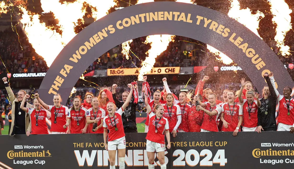 Bek Arsenal, Leah Williamson (tengah kiri) dan Kim Little memegang trofi saat merayakan kemenangan setelah final Piala Liga Wanita Inggris di Molineux, Wolverhampton, Inggris pada 31 Maret 2024. (Adrian DENNIS/AFP)