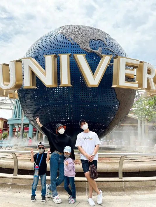 Gaya monokromatik saat liburan ke Universal Studio Singapore, Nycta Gina mengenakan oversized sweater dan bucket warna hitam. Sementara Rizky tampil senada dengan kaus putih dan celana hitam, serta topi baseball. (Foto: Instagram @missnyctagina)
