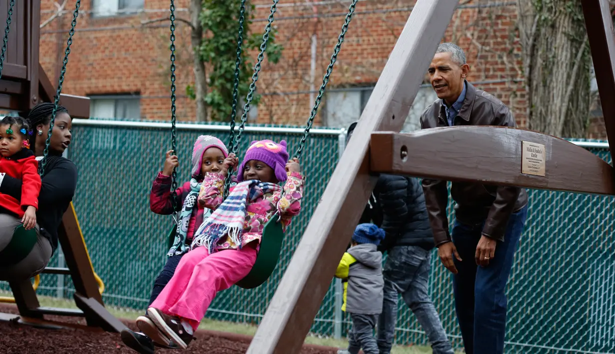 Presiden AS Barack Obama bersiap mendorong saat bermain ayunan dengan anak-anak di Washington DC, AS, Selasa (16/1). Obama menyumbangkan wahana bermain milik kedua putrinya yang dipasang di luar Oval Office. (AFP PHOTO / YURI GRIPAS)