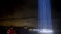 Orang-orang melihat pertunjukan cahaya saat mengunjungi penghormatan ringan untuk serangan 9/11 di Pentagon di Arlington, Virginia (10/9/2020). Pertunjukan tersebut adalah bagian dari peringatan skala kecil tahun ini karena pandemi virus corona. (Tasos Katopodis / Getty Images / AFP)