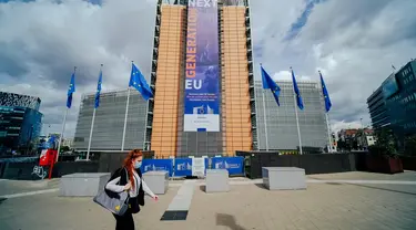 Seorang wanita yang mengenakan masker berjalan melewati markas Komisi Eropa di Brussel, Belgia, Selasa (7/7/2020). Komisi Eropa memprediksi Ekonomi Eropa akan menghadapi resesi lebih dalam akibat langkah-langkah pengendalian COVID-19 yang berkepanjangan. (Xinhua/Zhang Cheng)