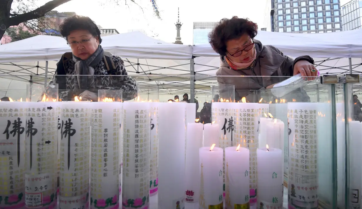 Dua orang wanita menyalakan lilin untuk mendoakan keberhasilan anak dan kerabatnya dalam mengikuti tes kemampuan Skolastik College tahunan di Seoul (23/11). Para ibu ini mengunjungi kuil Buddha Jogye untuk mendoakan anak mereka. (AFP Photo/Jung Yeon-Je)