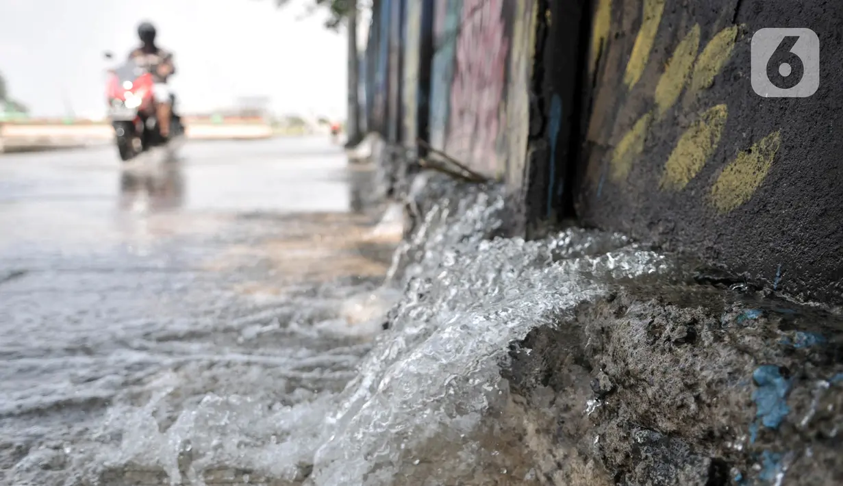 Pengendara motor melintasi rembesan air dari tembok saat banjir rob merendam Kompleks Perumahan Pantai Mutiara, Pluit, Jakarta, Minggu (7/6/2020). (merdeka.com/Iqbal S. Nugroho)