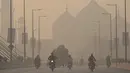Komuter melintasi jalan di tengah kondisi kabut asap di Lahore, Pakistan, pada 16 November 2021. Akibat kabut asap beracun tersebut, ratusan anak di Lahore dilaporkan mengalami penyakit gangguan pernapasan akibat menghirupnya. (Arif ALI/AFP)