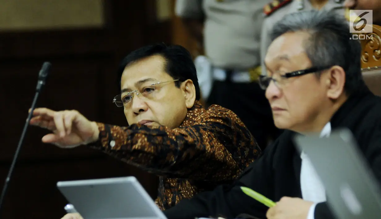 Terdakwa dugaan korupsi proyek e-KTP Setya Novanto (kanan) membetulkan letak mikrofon saat mengikuti sidang lanjutan di Pengadilan Tipikor, Jakarta, Kamis (11/1). Sidang mendengar keterangan empat orang saksi. (Liputan6.com/Helmi Fithriansyah)