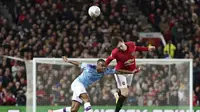 Penyerang Manchester City, Raheem Sterling berebut bola udara dengan bek Manchester United, Victor Lindelof pada pertandingan leg pertama semifinal Piala Liga Inggris di Old Trafford (7/1/2020). City menang 3-1 atas MU. (AP Photo / Jon Super)
