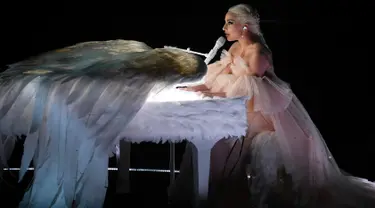 Penyanyi Lady Gaga tampil dengan piano putih berbalut sepasang sayap raksasa di panggung Grammy Awards 2018, New York,  Minggu (28/1). Bergaun baby pink yang memukau, Gaga membawakan lagu Joanne dan Million Reasons. (KEVIN WINTER/GETTY IMAGES/AFP)