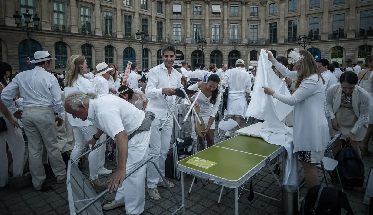 Peserta menyiapkan perlengkapan acara 'Diner en blanc' atau 'Makan Malam Putih' yang digelar di Place Vendome, Paris, Rabu (8/6). Ribuan orang mengenakan pakaian putih membawa meja, kursi dan keranjang penuh dengan makanan. (PHILIPPE LOPE/AFP)