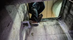 Demonstran memanjat keluar dari pintu masuk selokan setelah merangkak melalui salah satu terowongannya bawah tanah ketika mencoba mencari jalan untuk melarikan diri dari Universitas Politeknik Hong Kong di distrik Hung Hom, pada 19 November 2019. (Anthony WALLACE/AFP)