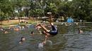 Orang-orang mendinginkan tubuh di sungai di tengah gelombang panas di Paraguari, Paraguay, Minggu (16/1/2022). Suhu Paraguay secara umum mencapai 41 derajat celsius. (AP Photo/Jorge Saenz)