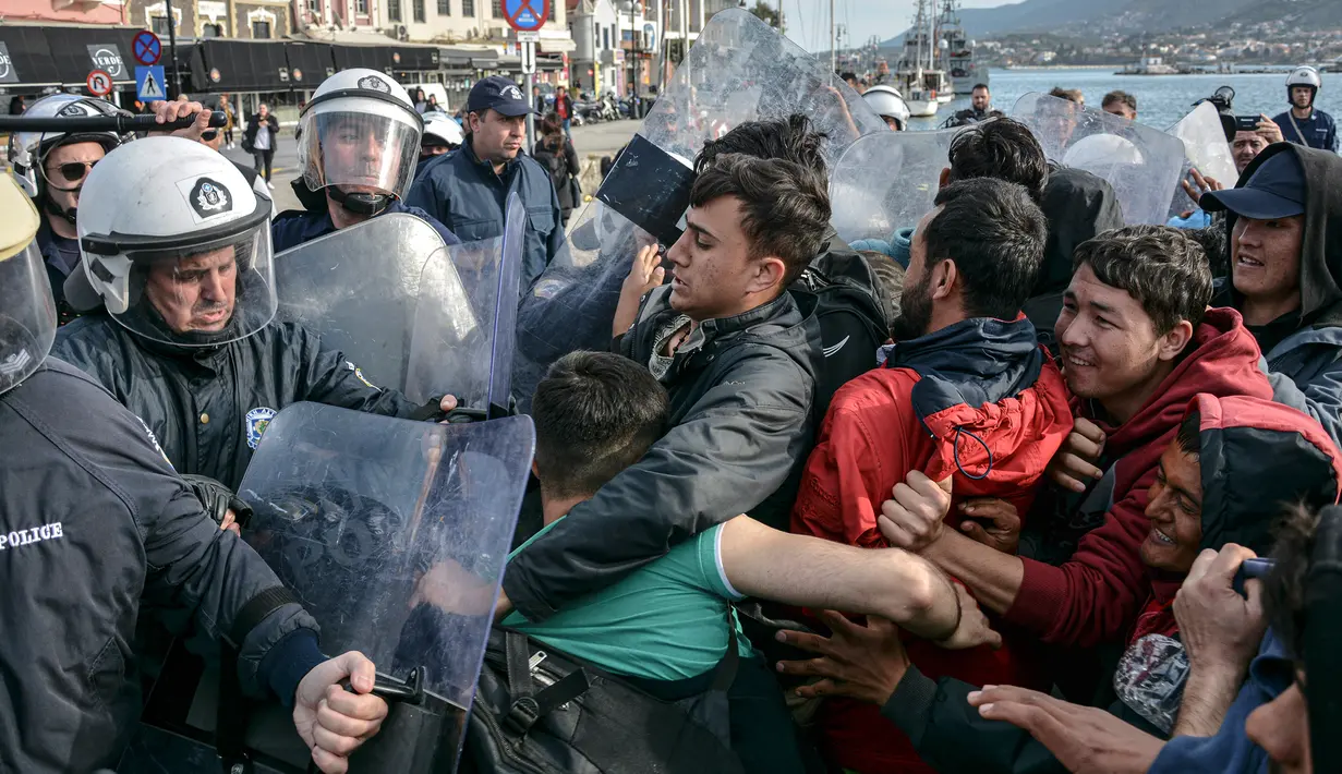 Para migran berkelahi dengan polisi Yunani di Pelabuhan Mytilene setelah penduduk setempat memblokir akses ke kamp pengungsi Moria di Pulau Aegean, timur laut Lesbos, Yunani, Selasa (3/3/2020). (AP Photo/ Panagiotis Balaskas)