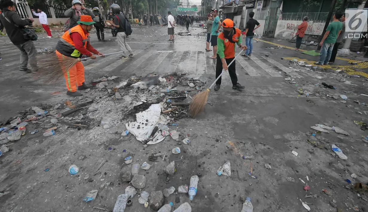 Petugas Penanganan Prasarana dan Sarana Umum (PPSU) atau Pasukan Oranye membersihkan sisa puing-puing pasca kerusuhan di kawasan Jakarta, Kamis (23/5/2019). Aksi unjuk rasa itu dilakukan menyikapi putusan hasil rekapitulasi nasional Pemilu serentak 2019. (Liputan6.com/Herman Zakharia)