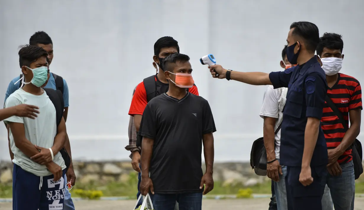 Seorang petugas Urusan Kelautan dan Perikanan Indonesia memeriksa suhu tubuh nelayan Myanmar ketika mereka dideportasi setelah ditahan selama delapan bulan di Banda Aceh (5/8/2020). Mereka ditangkap karena penangkapan ikan ilegal di perairan Aceh sepanjang selat Malaka. (AFP Photo/Chaideer Mahyuddin