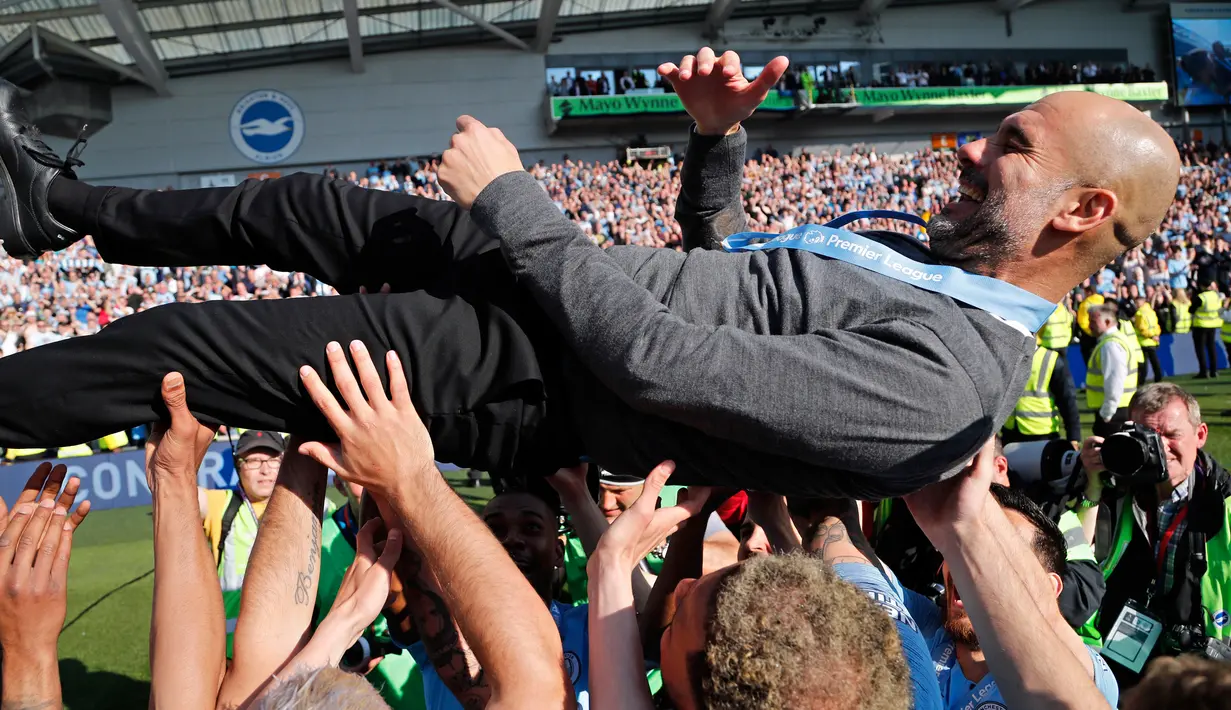 Pelatih Manchester City Pep Guardiola diangkat ke udara oleh para pemain usai mengalahkan Brighton di Stadion AMEX, Brighton, Inggris, Minggu (12/5). The Citizens menjadi yang terbaik di musim 2018-2019 setelah memenangi duel sengit dengan Liverpool hingga pekan terakhir. (AP Photo/Frank Augstein)