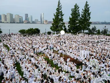 Ribuan orang berpakaian serba putih berkumpul dalam Diner en blanc di Rockefeller Park, New York, Rabu (17/7/2019). New York City Diner en Blanc adalah sebuah pesta makan malam rahasia dengan pakaian bernuansa putih yang diadopsi dari budaya Prancis. (Eric Vitale/Diner en Blanc International via AP)