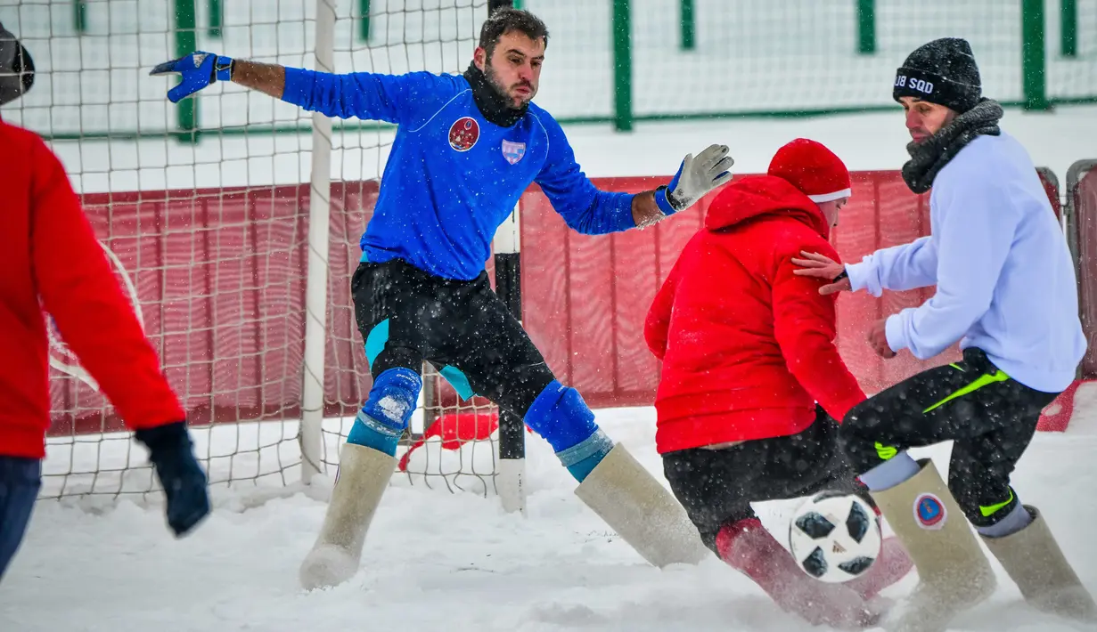 Seorang pemain menendang bola saat pertandingan persahabatan antara wartawan dan mahasiswa asing di lapangan bersalju di Nizhny Novgorod, Rusia, Minggu (21/1). Pertandingan digelar dalam menyambut Piala Dunia 2018 di Rusia. (AFP PHOTO/Mladen ANTONOV)