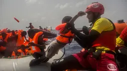 Petugas LSM Spanyol menyelamatkan anak imigran dari Afrika sub-Sahara di tengah Laut Mediterania, Selasa (25/7). Juru bicara penjaga pantai Italia mengatakan sekitar 260 migran telah diselamatkan dari perahu yang berbeda pada hari itu. (AP/Santi Palacios)