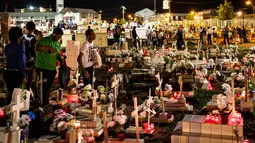 Keluarga dan kerabat mengunjungi makam sambil menaruh bunga dan lilin di pemakaman Cayenne di Guyana Prancis (1/11). All Saints Day adalah suatu perayaan keagamaan yang dirayakan pada tanggal 1 November. (AFP Photo/Jody Amiet)