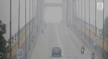 Sejumlah kendaraan melintas di atas jembatan yang diselimuti kabut asap di Kota Pekanbaru, Riau, Selasa (10/9/2019). Kabut asap akibat kebakaran hutan dan lahan (karhutla) tersebut menurunkan jarak pandang dan kualitas udara turun ke status tidak sehat. (Liputan6.com/Faizal Fanani)