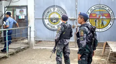 Polisi bersenjata lengkap berjaga di depan gerbang sebuah penjara di kota Kidapawan, selatan Filipina, Rabu (4/1). Sekelompok pria bersenjata dilaporkan menembus masuk penjara itu dan berhasil membebaskan lebih dari 150 tahanan. (Ferdinandh CABRERA/AFP)