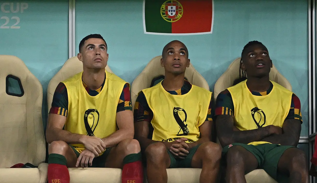Cristiano Ronaldo (kiri) duduk di bangku cadangan bersama Joao Mario (tengah) dan Rafael Leao (kanan) selama pertandingan sepak bola babak 16 besar Piala Dunia 2022 antara Portugal dan Swiss di Stadion Lusail, Lusail, Qatar, Selasa (6/12/2022). Keputusan mencadangkan Ronaldo diambil oleh sang pelatih, Fernando Santos. (Paul ELLIS / AFP)