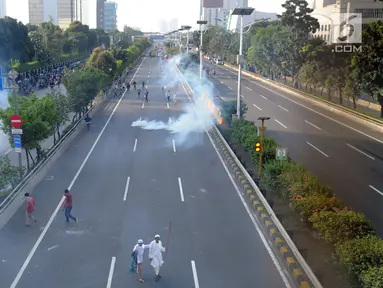 Massa menghindari gas air mata saat bentrok dengan polisi di jalan tol dalam kota di kawasan Slipi, Jakarta, Rabu (22/5/2019). Jalan tol  dalam kota sempat ditutup sekitar setengah jam, dan massa dihalau petugas ke arah kemanggisan. (merdeka.com/Arie Basuki)