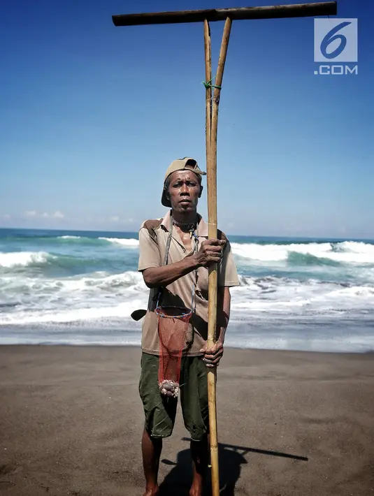Marsiono, berpose memegang sebilah bambu untuk mencari undur-undur atau yutuk di bibir Pantai Bocor, Kabupaten Kebumen, Jawa Tengah, Sabtu (05/5). Aktivitas tersebut telah berjalan puluhan tahun. (Liputan6.com/Fery Pradolo)