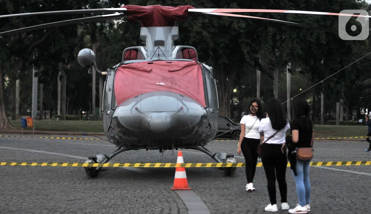 Warga berfoto dengan helikopter TNI yang terparkir di kawasan Monas, Jakarta, Rabu (16/10/2019). Kehadiran empat helikopter TNI/Polri yang akan digunakan dalam apel pengamanan pelantikan presiden dan wakil presiden tersebut menarik perhatian pengunjung Monas. (merdeka.com/Iqbal Nugroho)