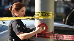 Petugas wanita memasang garis polisi di sekitar restoran cepat saji, di Hollywood, California setelah aksi penyerangan dengan pisau, Selasa (31/1). Sebelumnya, seorang pria melakukan penusukan membabi-buta di jalan dan pengunjung restoran (Robyn Beck/AFP)