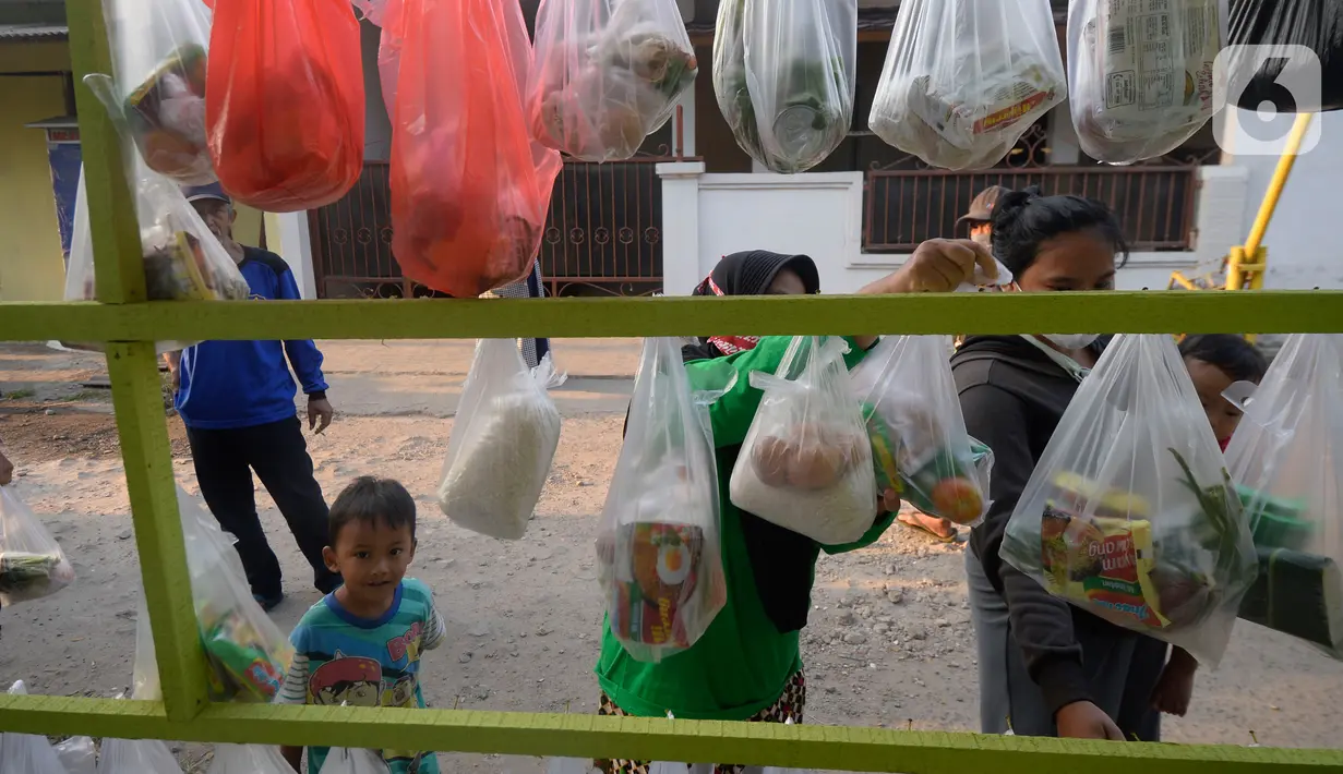 Warga sekitar perumahan Villa Pamulang mengambil paket sembako gratis bernama “Jumat Berkah” yang digantung di Tangerang Selatan, Jumat (28/8/2020). Setiap hari Jumat selama pandemi, warga perumahan itu mendonasikan sembako untuk warga sekitar yang terdampak COVID-19. (merdeka.com/Dwi Narwoko)