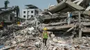 Para pekerja mengenakan pakaian hazmat menyemprotkan disinfektan untuk mensterilkan puing-puing bangunan yang runtuh di Mandalay pada 2 April 2025. (Sai Aung MAIN/AFP)