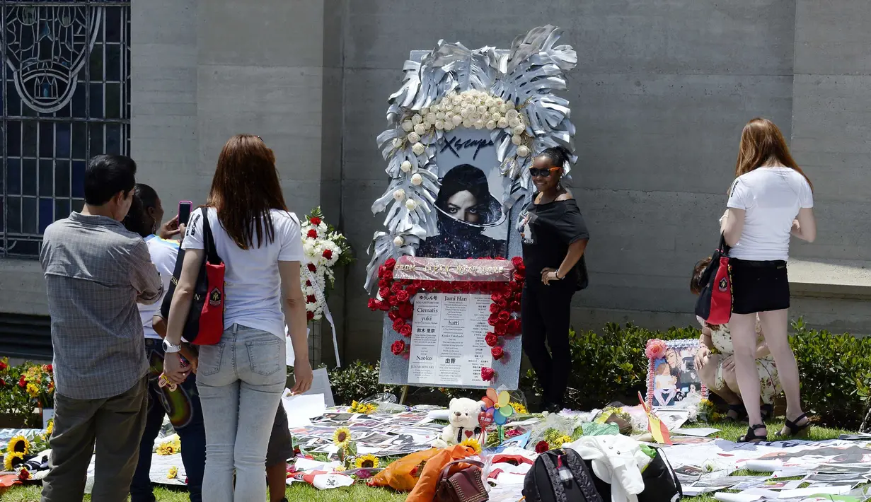 Seorang fans berpose dengan foto Michael Jackson di depan pintu masuk makam di mana Jackson dikebumikan di Forest Lawn Memorial Park-Glendale, California, Rabu (25/6/14). (REUTERS/Kevork Djansezian)