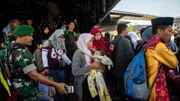 Seorang pria membawa anaknya ketika mereka tiba dalam penerbangan evakuasi oleh TNI dari Palu di Surabaya, Kamis (4/10). Sebanyak 1.411 orang telah dikonfirmasi tewas akibat bencana tersebut. (AFP Photo/Juni Kriswanto)