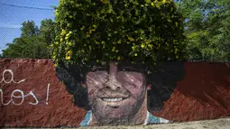 Sebuah mural dari mendiang legenda sepak bola dunia, Diego Maradona menghiasi yayasan "Lugar del Sol" untuk anak-anak miskin di Buenos Aires, Argentina, Rabu (24/11/2021). Peringatan pertama kematian Maradona digelar pada 25 November 2021. (AP Photo/Rodrigo Abd)