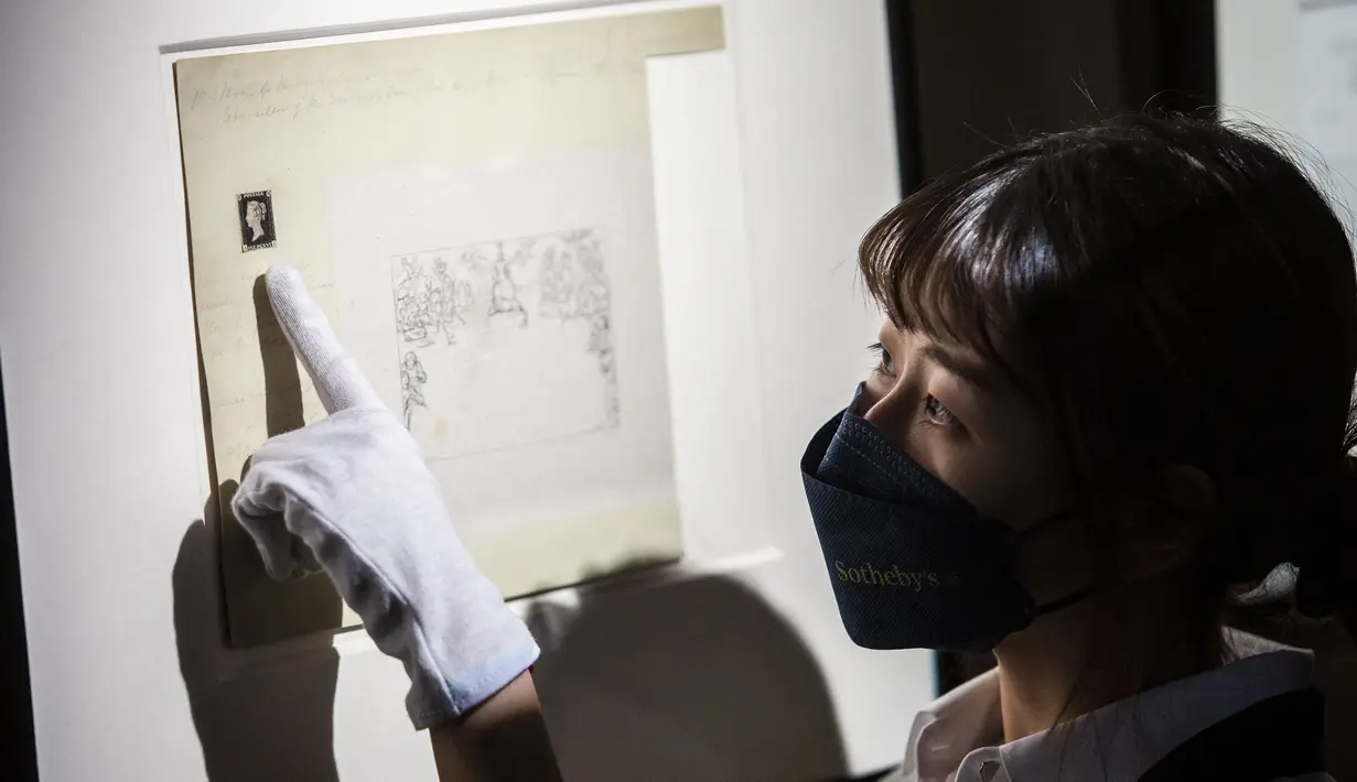Petugas menunjuk ke prangko pertama di dunia, Penny Black, yang dipajang menjelang lelangnya, di Sotheby Hong Kong, Selasa (26/10/2021). Penny Black merupakan prangko berperekat pertama di dunia yang menampilkan sosok Ratu Victoria dan tercetak dengan background warna hitam. (ISAAC LAWRENCE / AFP)