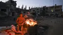 Seorang pemuda Palestina bersiap untuk memasak jagung dekat bangunan yang hancur selama konflik antara Hamas dan Israel pada Mei 2021 di Beit Hanun, Jalur Gaza, Senin (7/6/2021). Hamas dan Israel gencatan senjata setelah perang selama 11 hari. (MAHMUD HAMS/AFP)