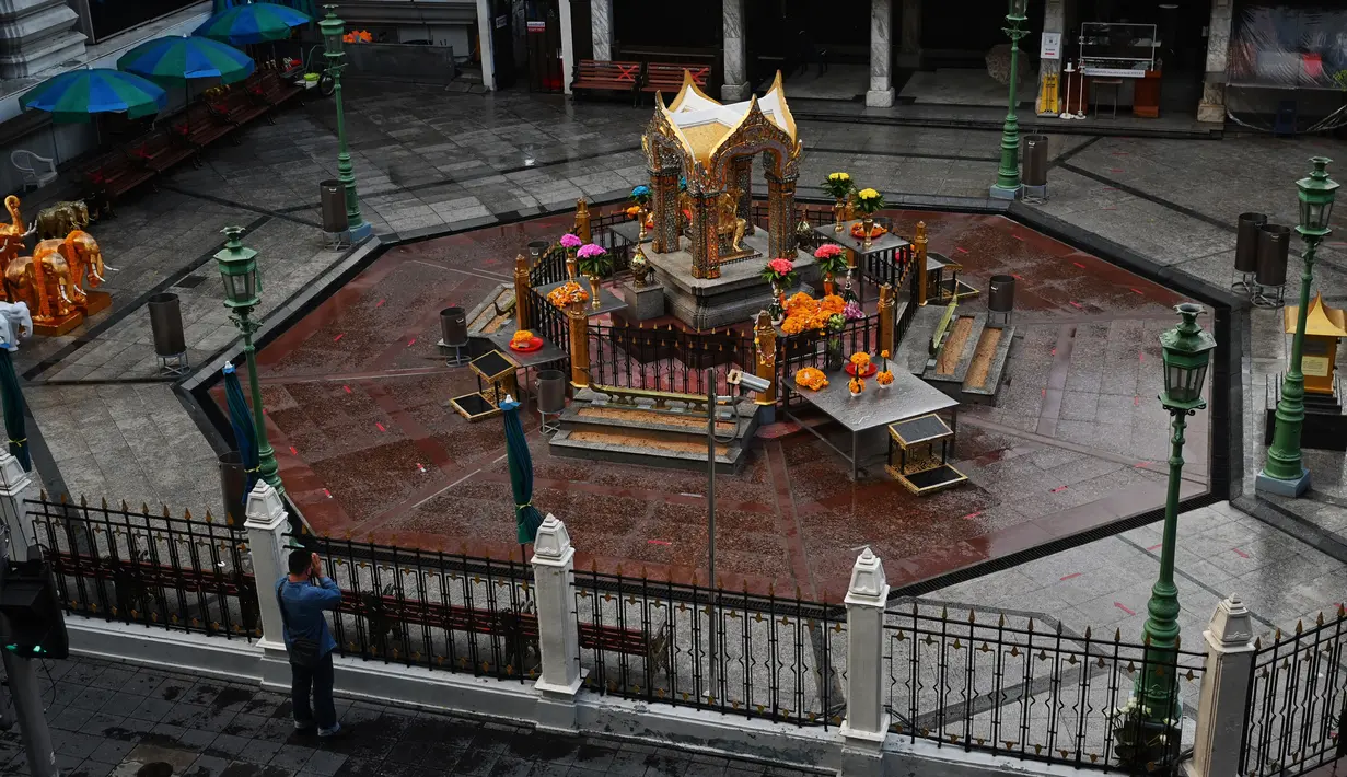 Seorang pria berdoa di luar gerbang Kuil Erawan pada hari pertama penguncian COVID-19 yang lebih ketat di Bangkok, Senin (12/7/2021).  Thailand menerapkan lockdown untuk menekan laju penyebaran virus corona pada Senin, 12 Juli 2021 di Bangkok dan provinsi sekitarnya. (Lillian SUWANRUMPHA/AFP)